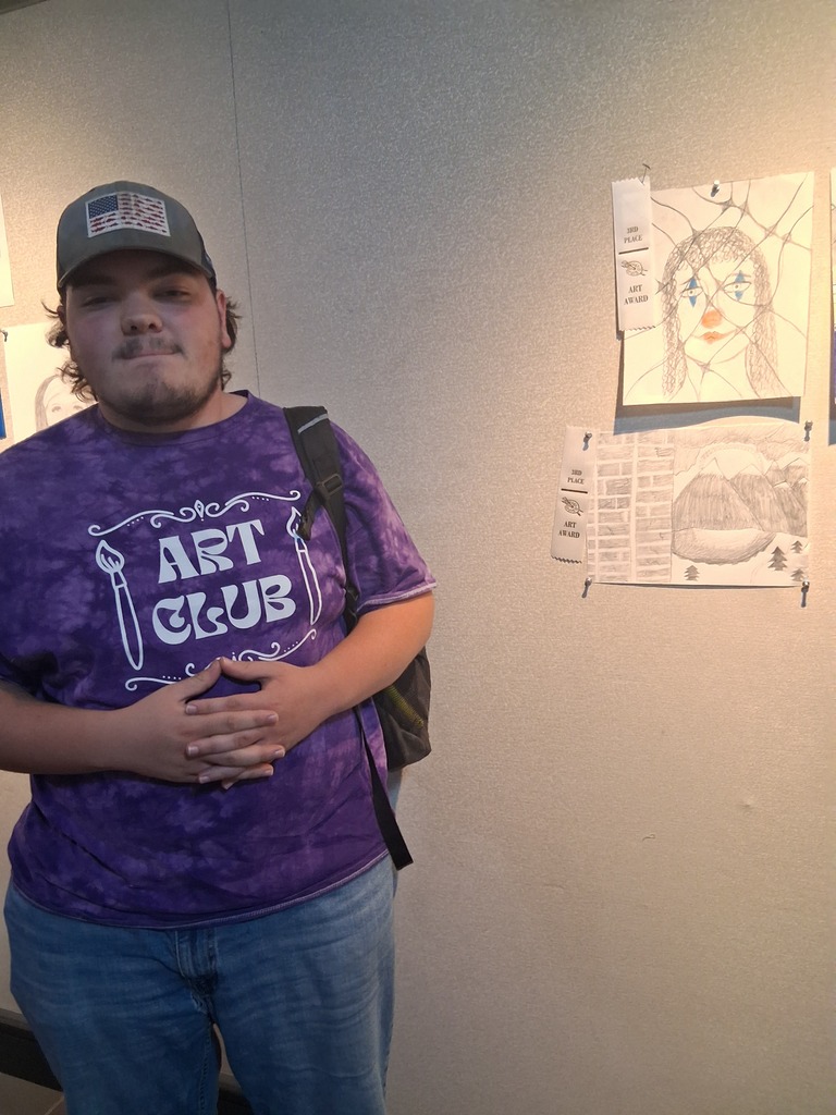 Student stands in front of their artwork.