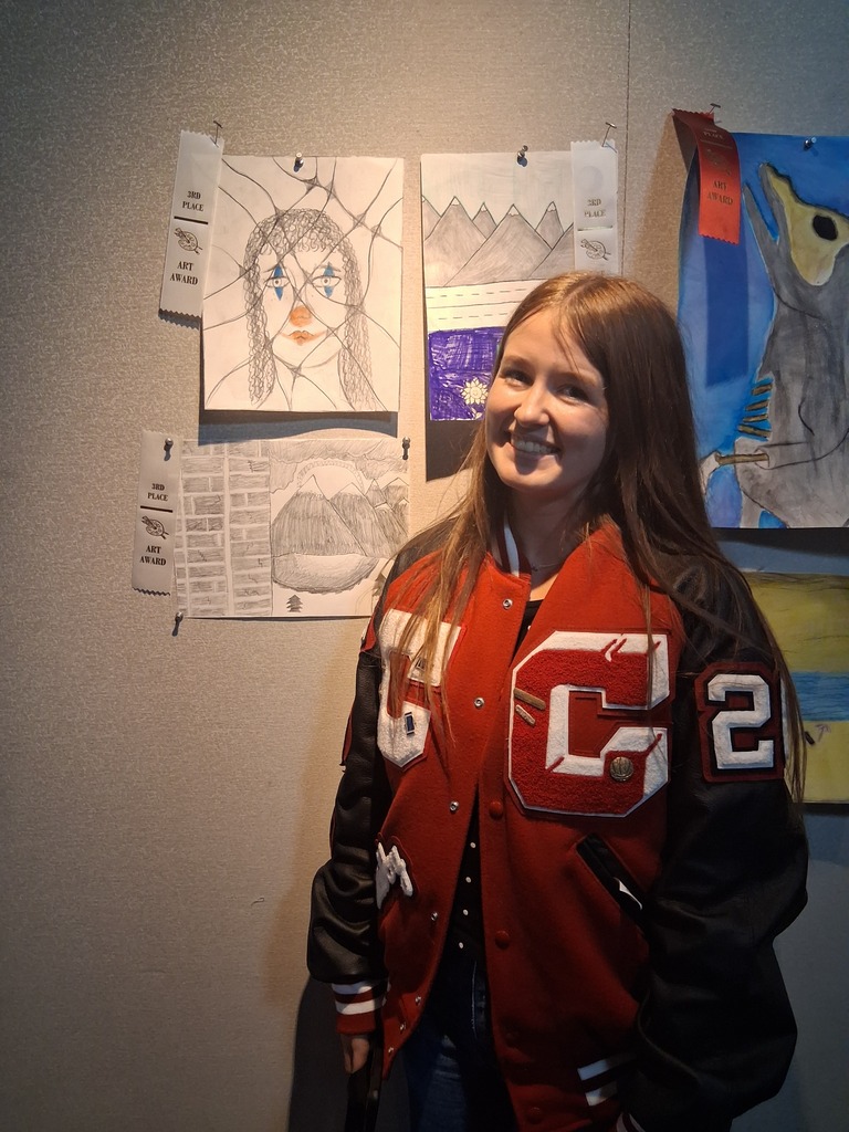 Student stands in front of their artwork.