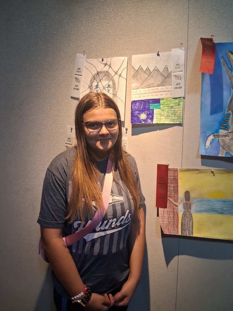 Student stands in front of their artwork.