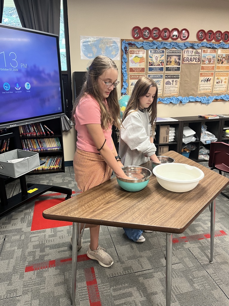 Girls doing experiment with hands in water in bowls 
