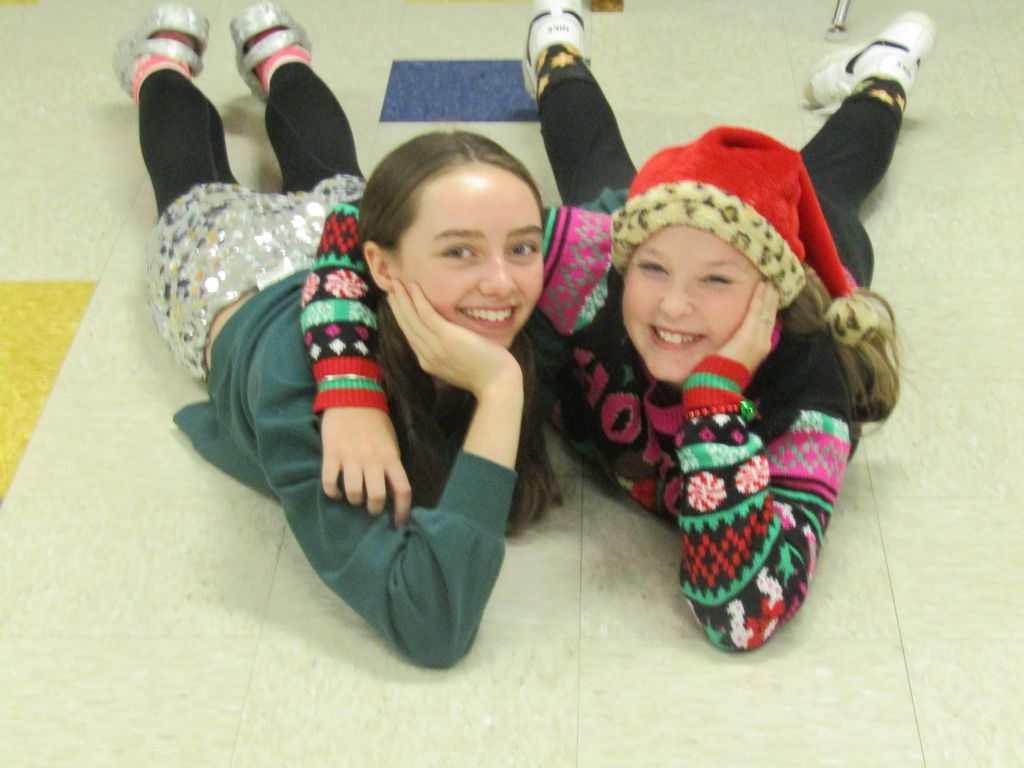 friends laying on the ground smiling at the camera in holiday sweaters