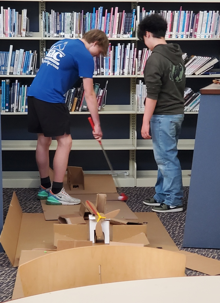 A boy hitting a golf ball as the other looks on