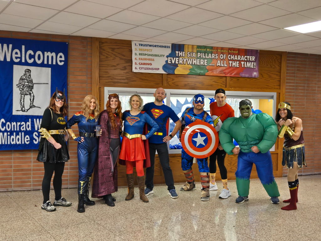Teachers dressed as superheroes in a lobby