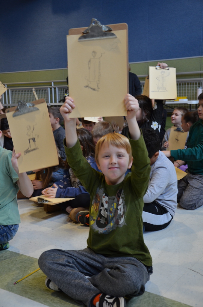 A student triumphantly holding up his masterpiece from the assembly.