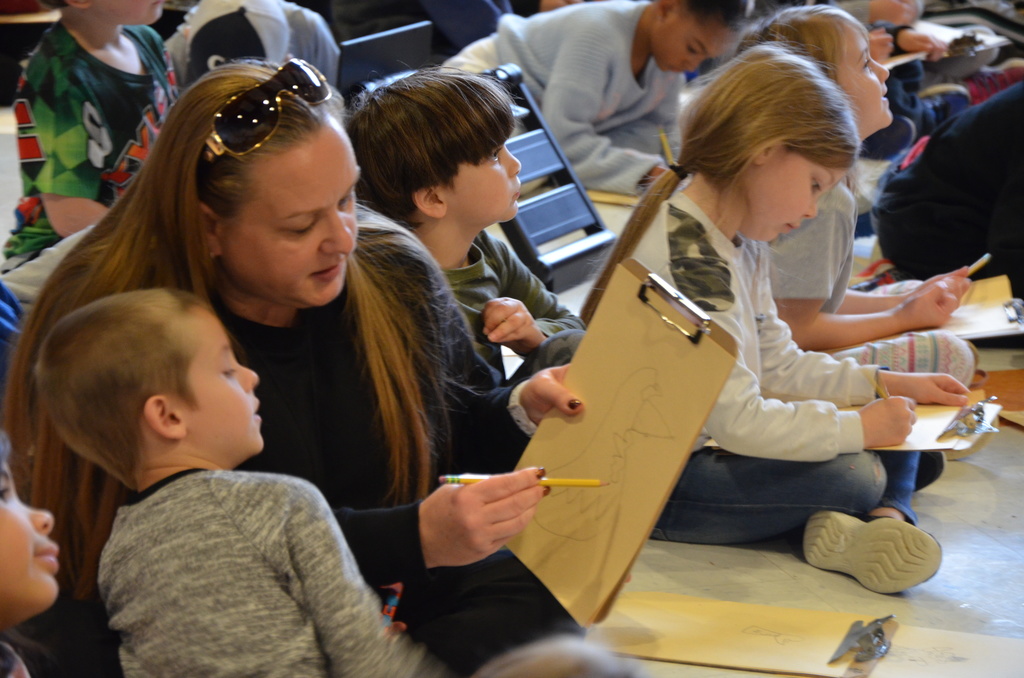 a teacher pointing to a drawing with a student watching