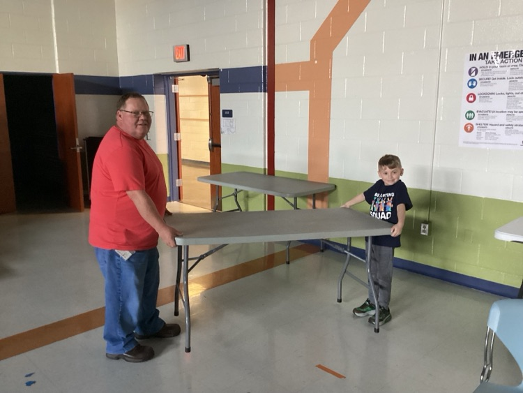 Mr. Hernley and a student moving a table 