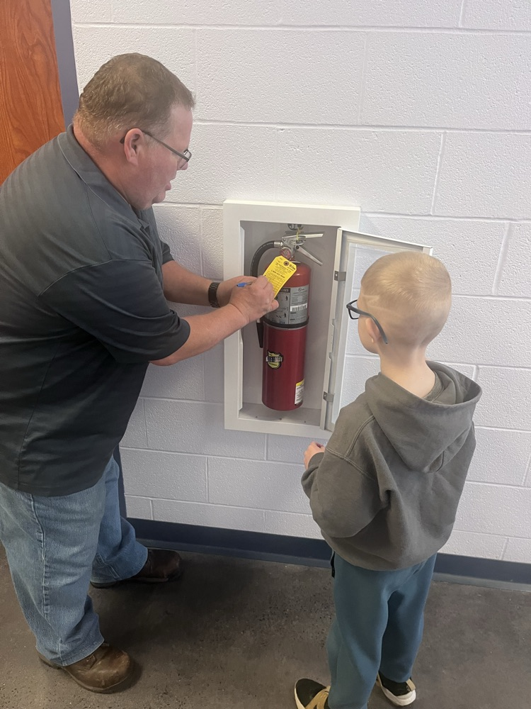 Mr Hernley and a student inspecting a fire extinguisher 