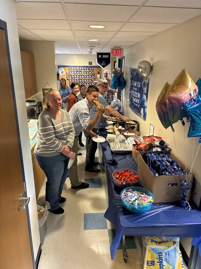 Teachers gathering around a table with food on it