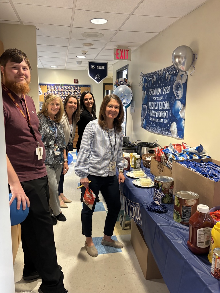 Teachers gathering around a table with food on it