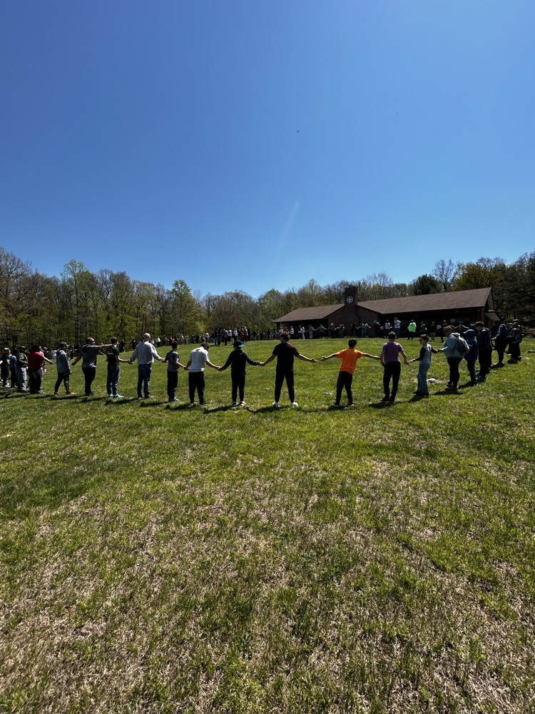 students in a large circle holding hands for a teamwork game