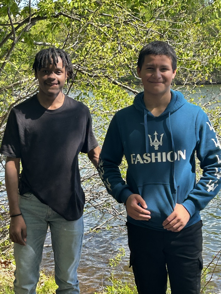 two students standing near a lake