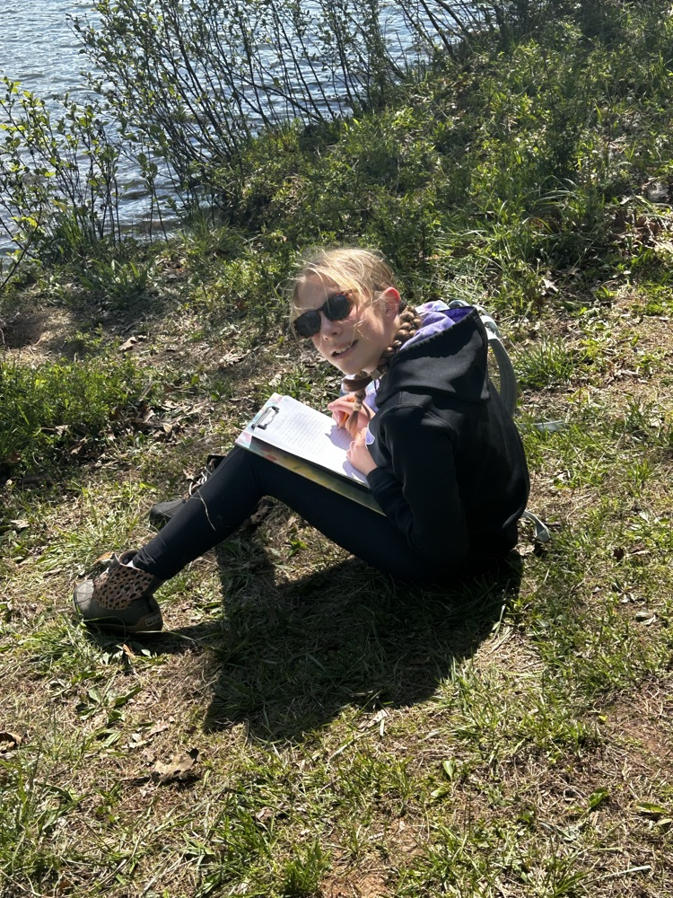 student with sunglasses sitting near a lake
