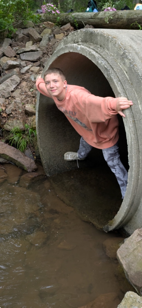 student exiting a large concrete tube