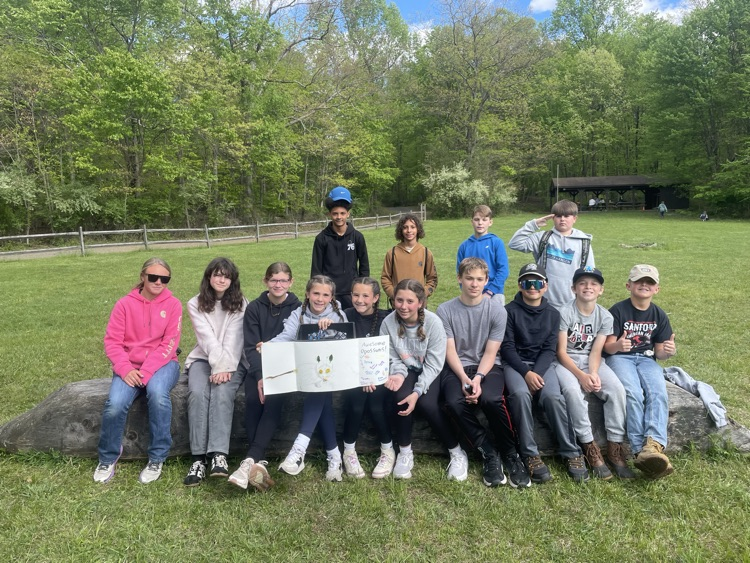 students sitting on a log with a sign