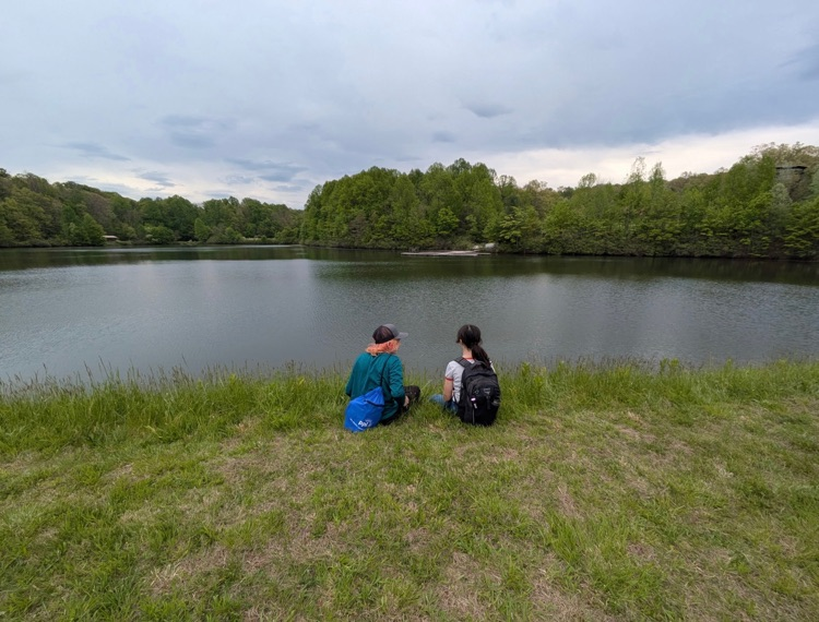 two student sitting facing a lake