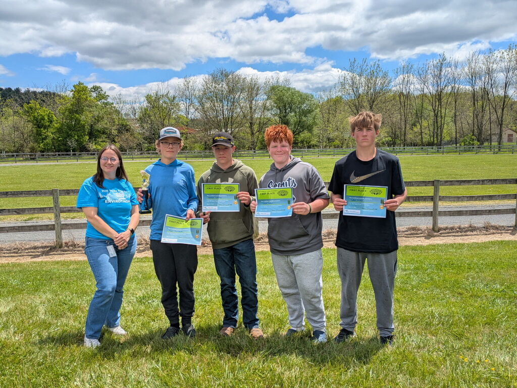 Students stΓ€ndig in front of a fence holding certificates.