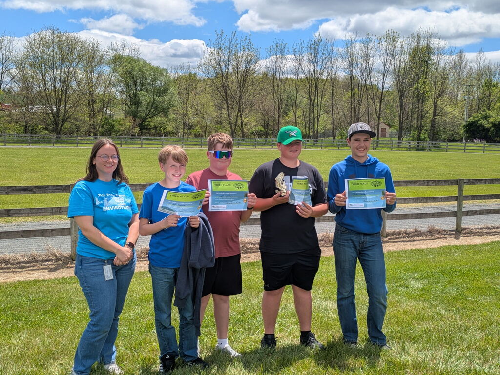 students in front of a fence with certificates