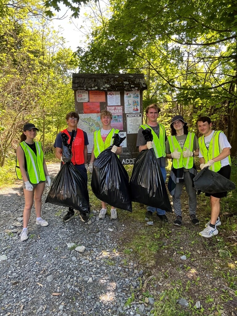 students holding trash bags in a wooded area