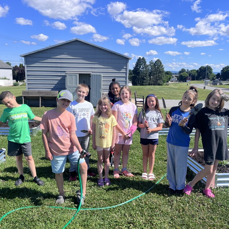group of students standing with the hoses and the little shovels they used to weed