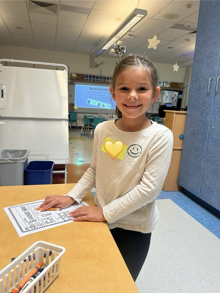 student writing their name in their kindergarten classroom