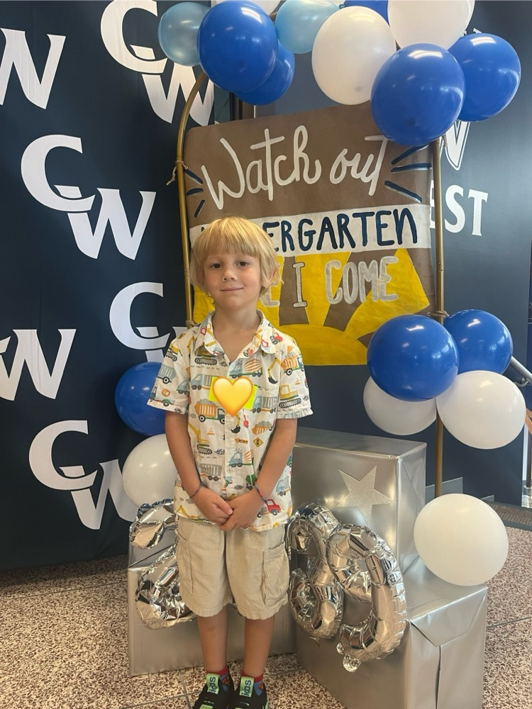 student posing with kindergarten sign