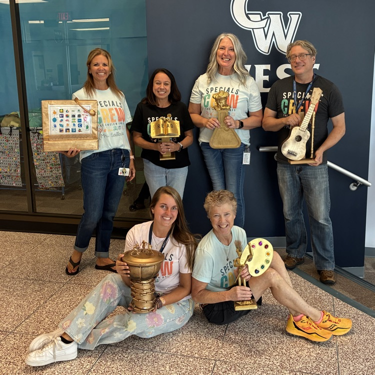 specialist teachers standing with their golden trophies. two are sitting