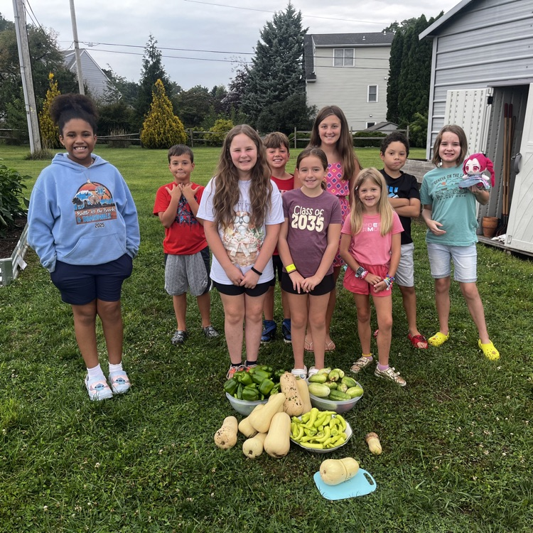 students standing with the vegetables they harvested