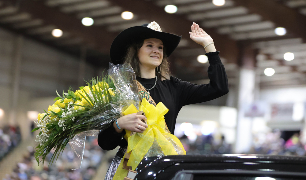 Montgomery County Fair Queen Avery McCartney waves while holding yellow roses while riding in the back of a pickup truck.