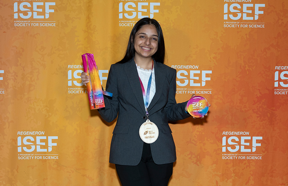 Aarushi Pandey wearing a gold medal and holding two awards.