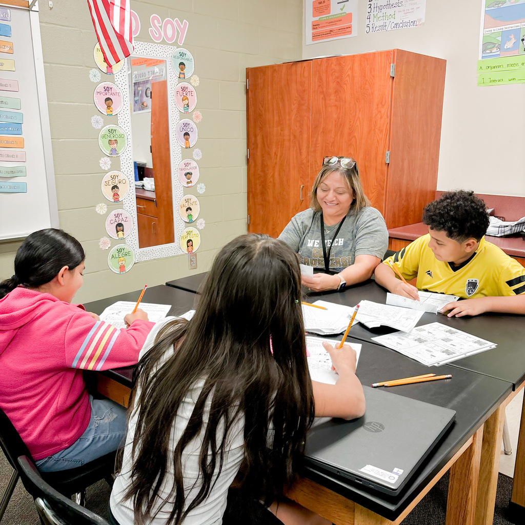 Paraprofessional with a group of students writing on paper