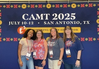4 teachers standing in front of a poster