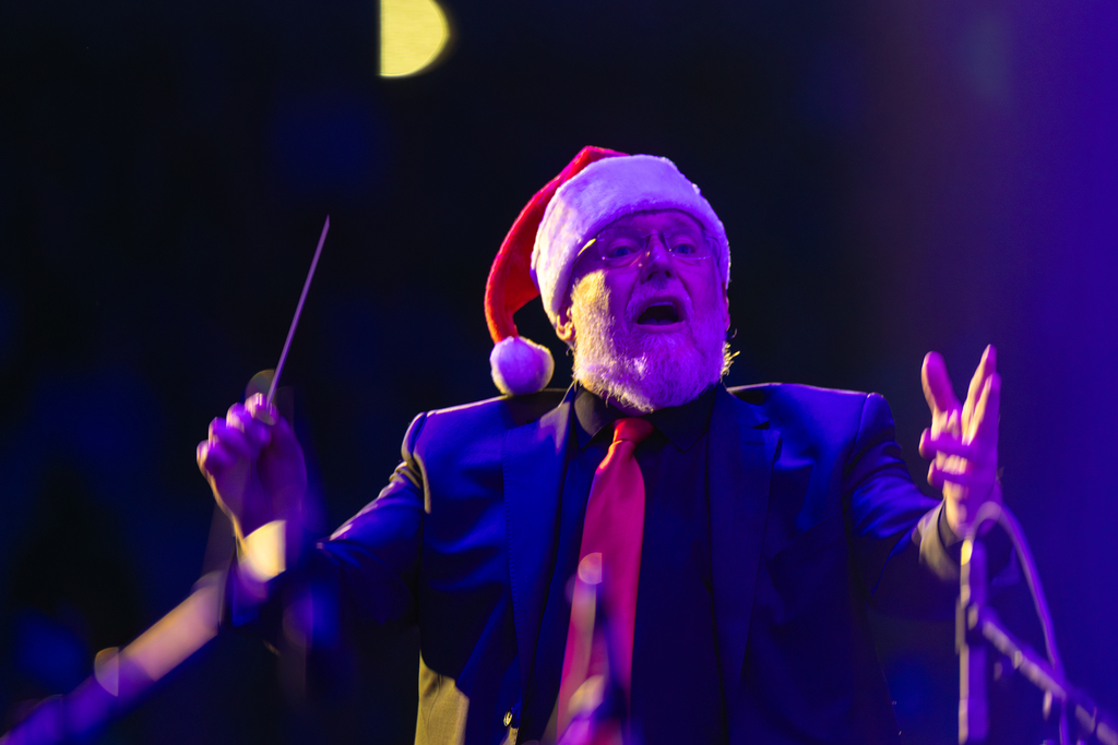 A conductor in a Santa hat directing his students.