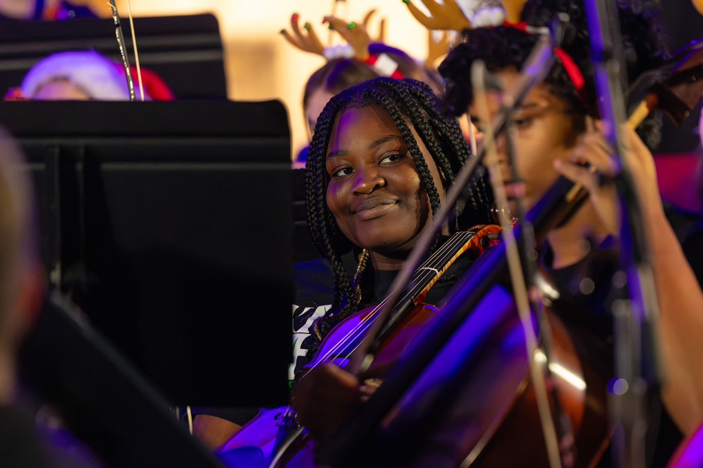 A student smiles while playing an instrument.