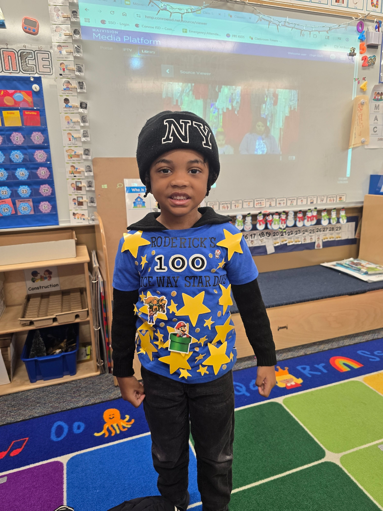 An elementary student smiling and wearing a shirt covered in stars.
