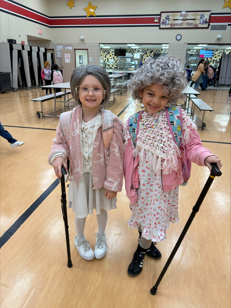 Two elementary students dressed up for the 100th Day of School in the school cafeteria.