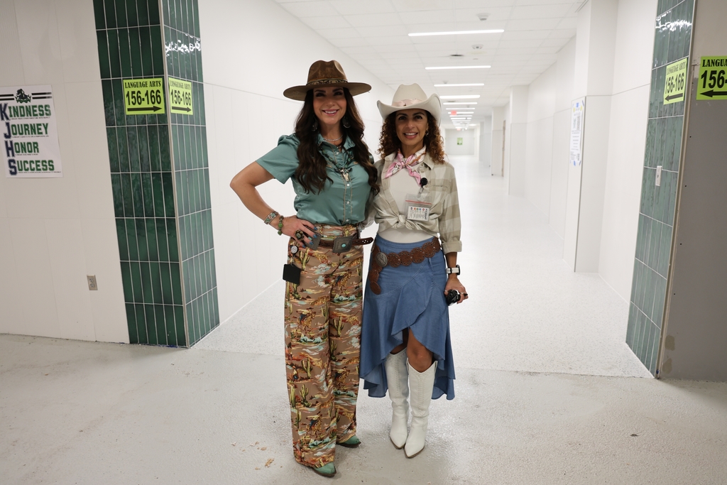Two staff members in Western outfits in a hallway.