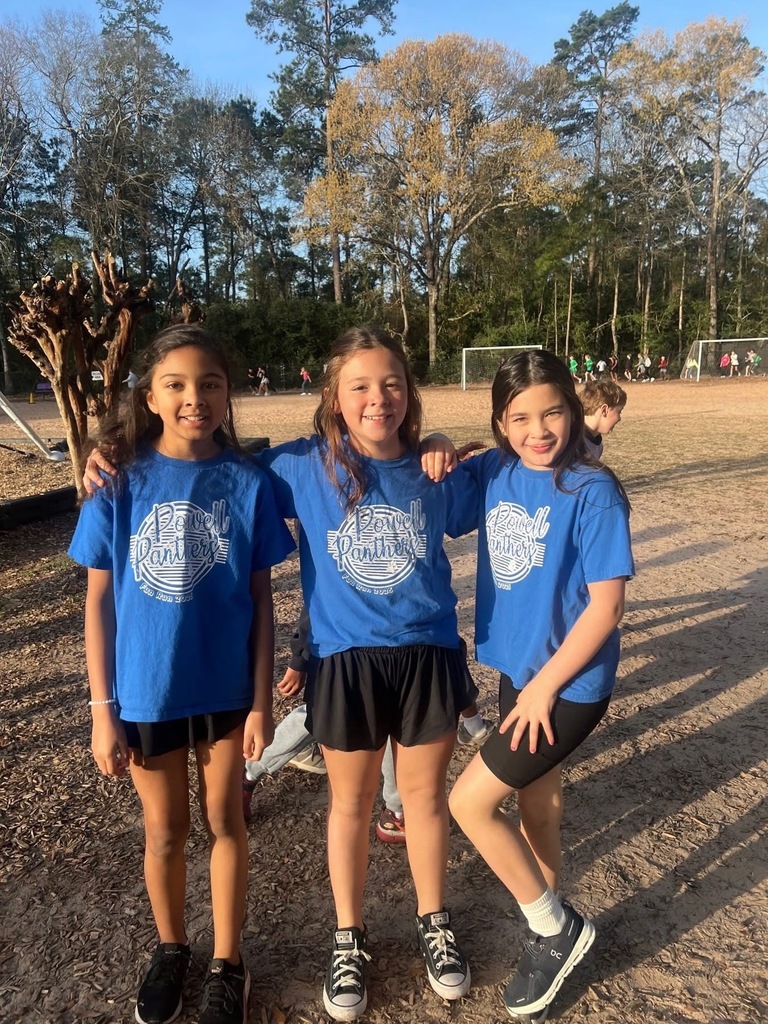 Three students wearing matching outfits are at the playground.