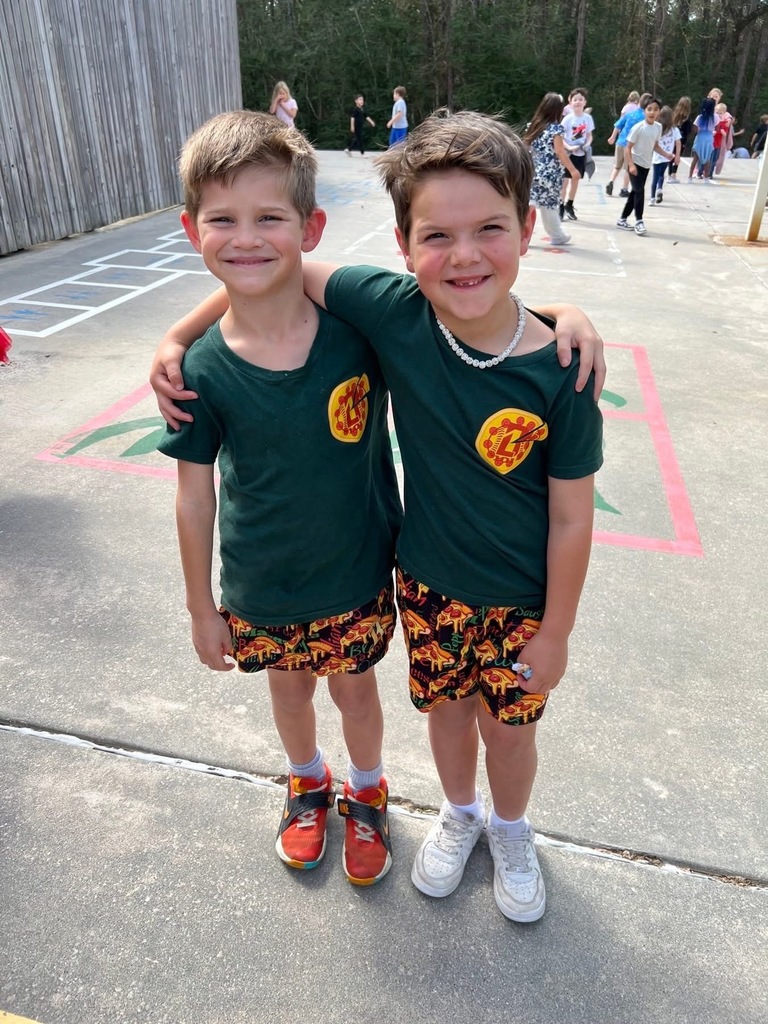 Two students side-hugging in matching outfits, smiling at the camera.
