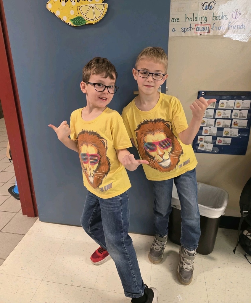 Two boys in matching outfits are posing with a shaka hand sign, smiling.