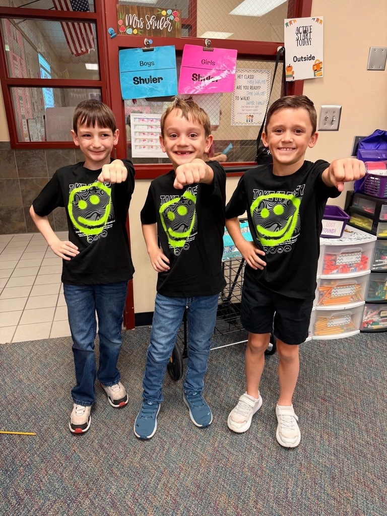 Three boys in matching shirts pose with a fist bump.