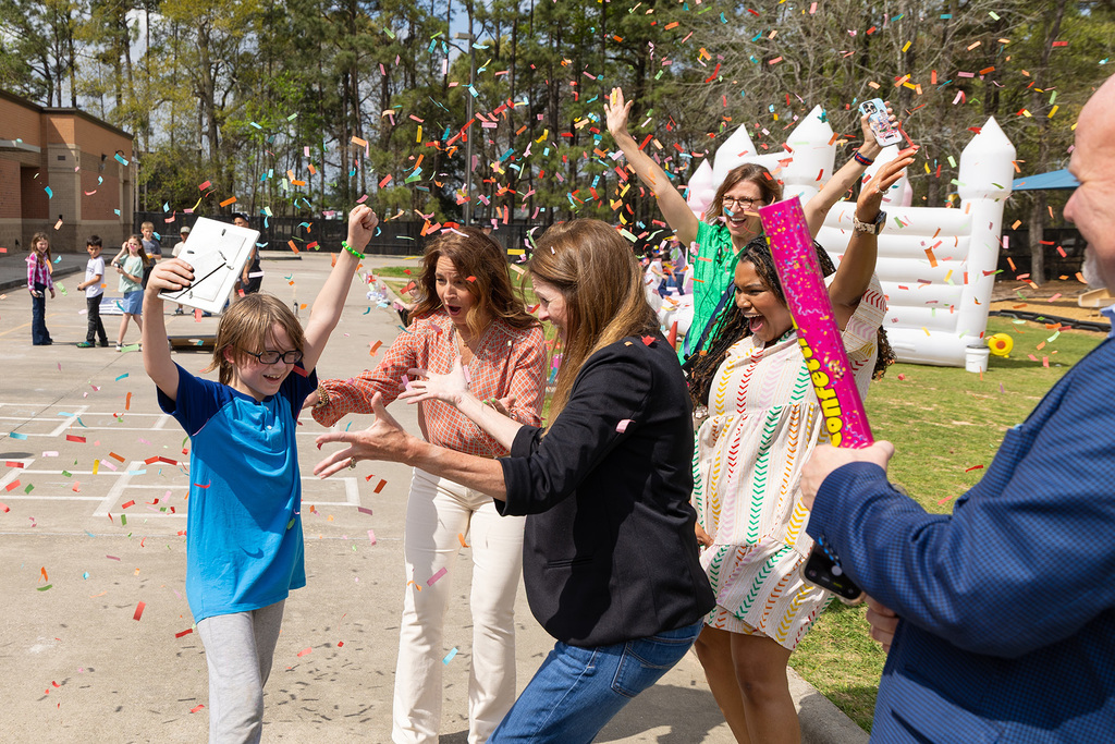 Student celebrates outdoors with staff as confetti falls during recognition surprise.