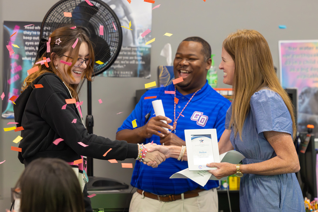 Student shakes hands with board member while receiving recognition certificate.