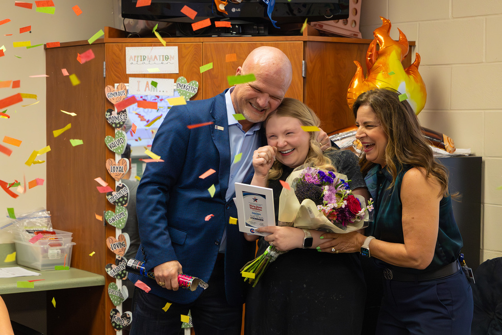 Superintendent and board member celebrate with confetti as educator smiles during recognition.