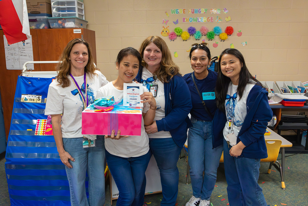 Group of staff pose with educator holding certificate and gift box.