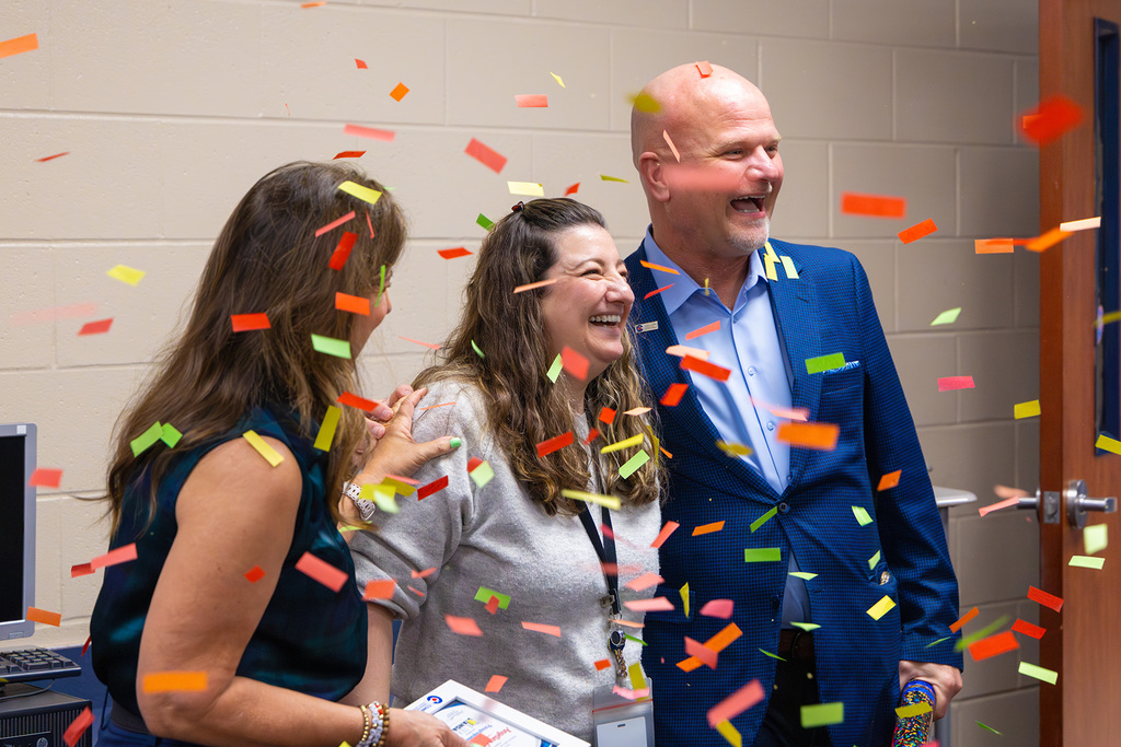 Board member and superintendent celebrate with confetti around smiling award recipient.