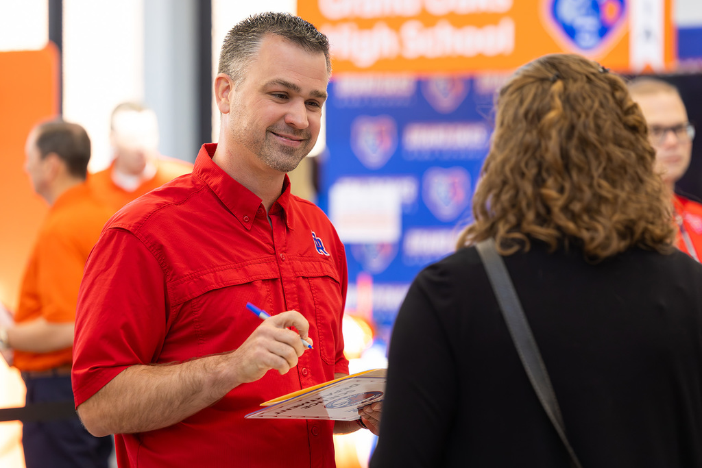 Administrator taking notes while speaking to a potential job candidate.