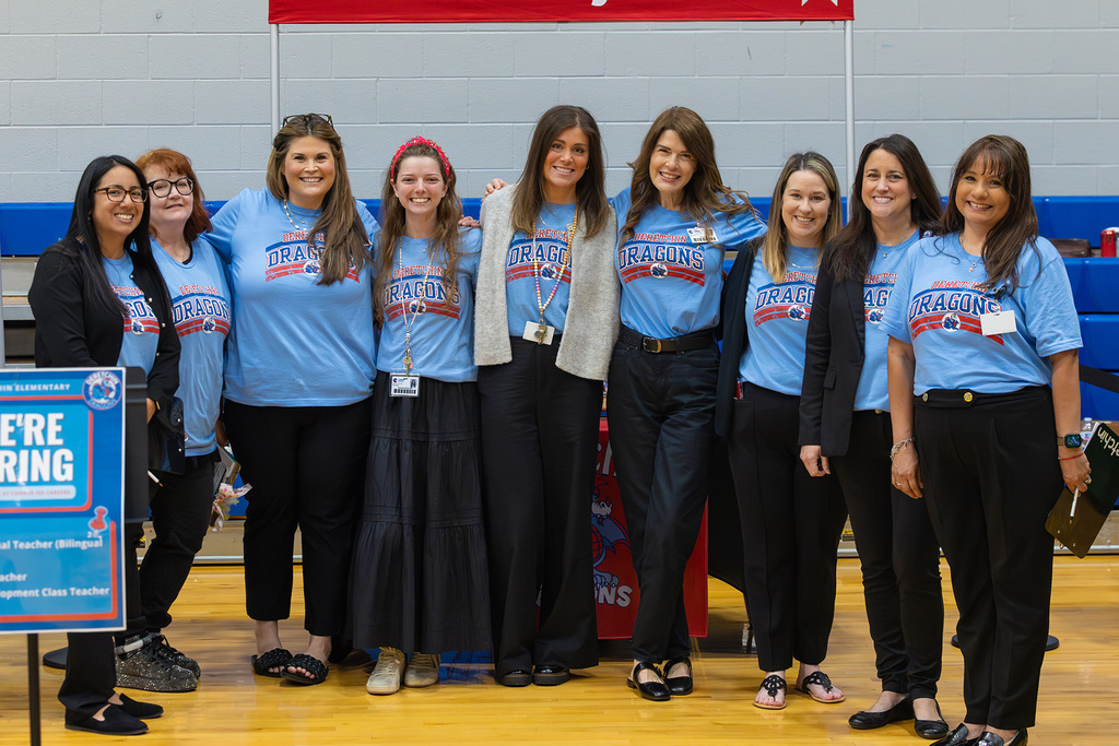 Group of nine educators in matching light blue shirts.