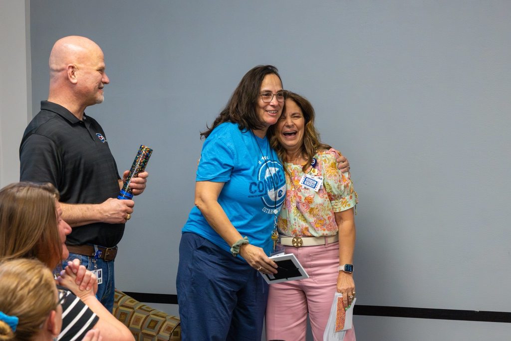 Staff member hugs Board President after earning award.