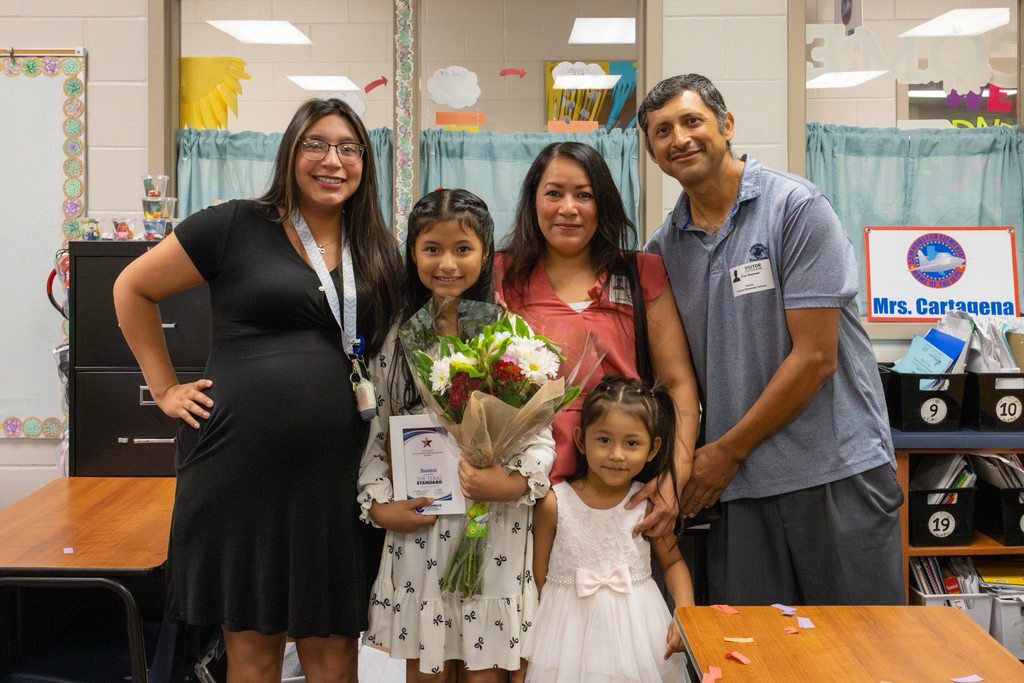 Family with student holding award plaque and flowers.