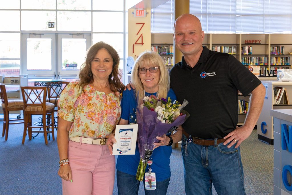 Superintendent and Board President with staff member holding award plaque.